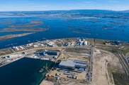 Aerial view of an industrial port facility alongside coastal wetlands and estuary in Portugal's Centro Region, illustrating integrated climate change mitigation through port decarbonization and coastal ecosystem restoration